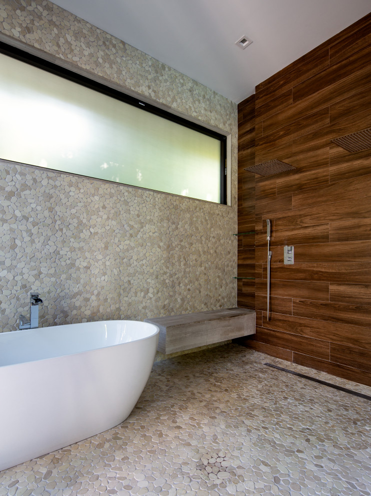 Design ideas for a contemporary bathroom in Miami with a freestanding tub, a curbless shower, brown tile, wood-look tile, beige walls, pebble tile floors, beige floor, a sliding shower screen and a niche.