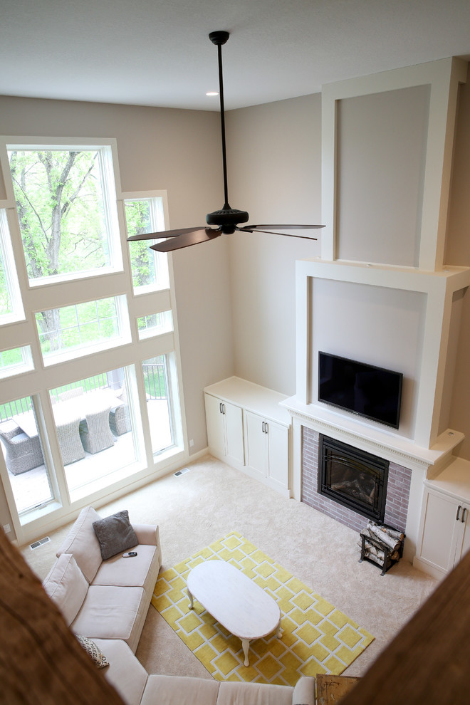 Example of a transitional loft-style carpeted home design design with beige walls, a standard fireplace, a brick fireplace and a wall-mounted tv
