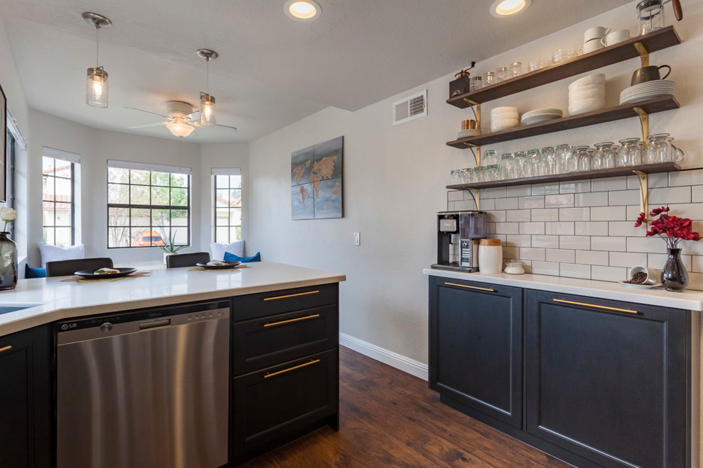 Mid-sized transitional u-shaped medium tone wood floor and brown floor enclosed kitchen photo in Los Angeles with an undermount sink, shaker cabinets, black cabinets, quartzite countertops, gray backsplash, ceramic backsplash, stainless steel appliances and no island