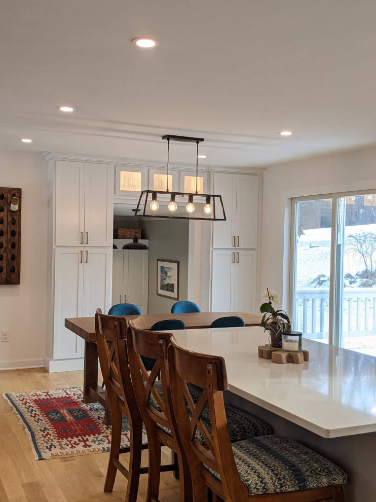 Exempel på ett mellanstort klassiskt vit vitt kök, med en undermonterad diskho, skåp i shakerstil, vita skåp, bänkskiva i kvartsit, vitt stänkskydd, stänkskydd i tunnelbanekakel, rostfria vitvaror, ljust trägolv, en köksö och brunt golv
