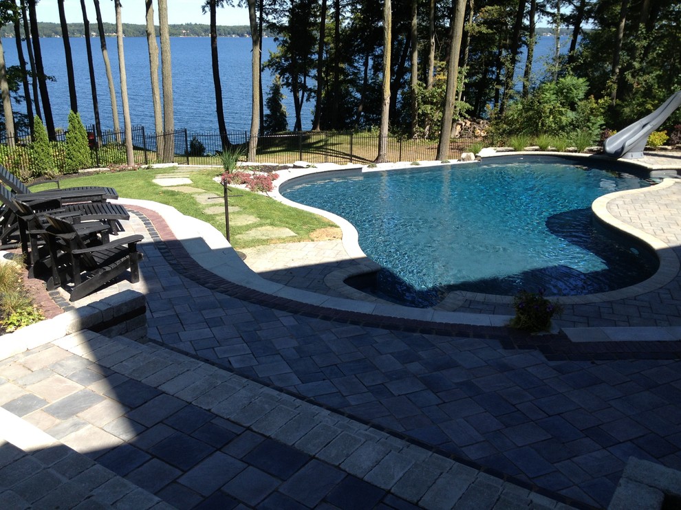 This is an example of a large contemporary sloped partial sun garden in Toronto with a water feature and natural stone pavers.