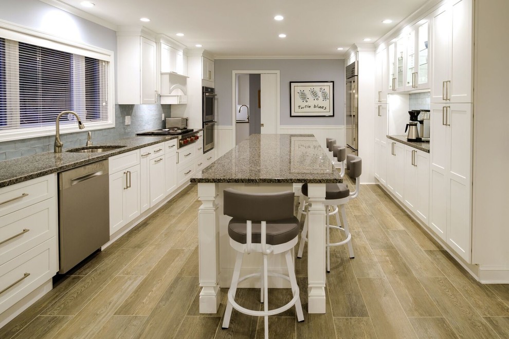 Inspiration for a mid-sized transitional u-shaped porcelain tile eat-in kitchen remodel in Orange County with an undermount sink, shaker cabinets, white cabinets, granite countertops, blue backsplash, glass tile backsplash, stainless steel appliances and an island