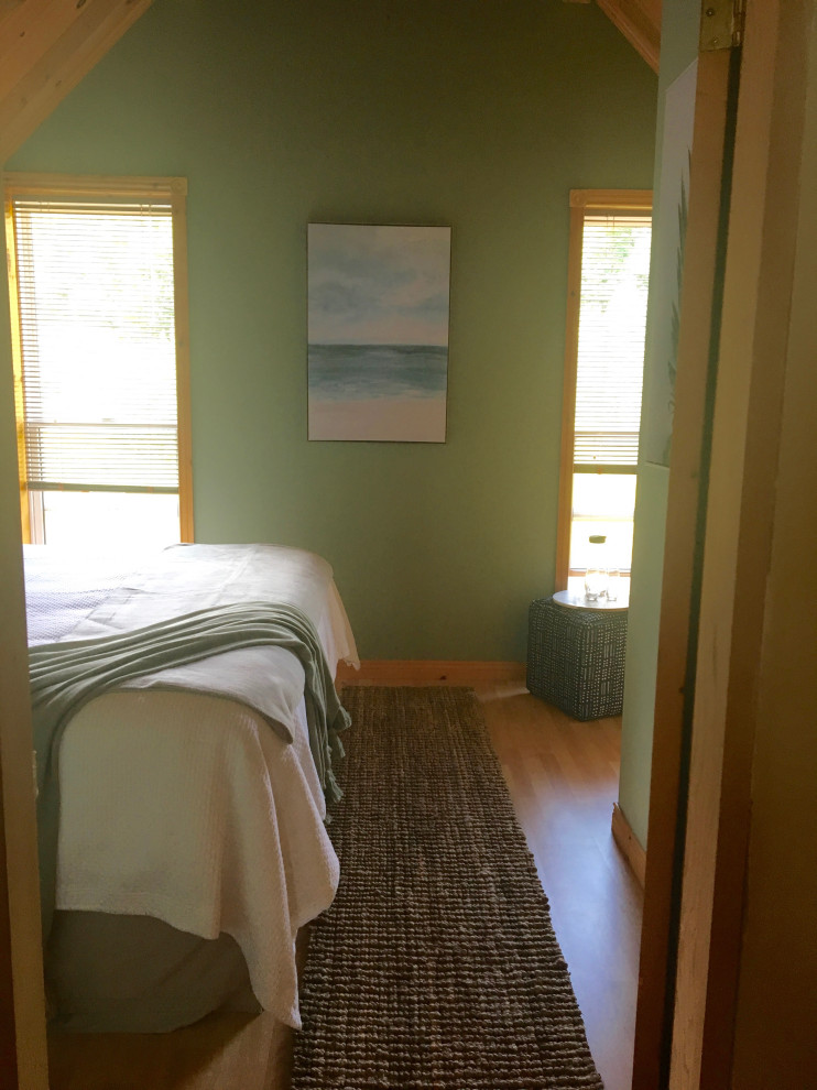 This is an example of a small beach style guest bedroom in Other with green walls, laminate floors and orange floor.