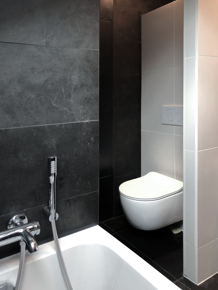 Modern inredning av ett stort badrum, med luckor med profilerade fronter, ett undermonterat badkar, en dusch i en alkov, en vägghängd toalettstol, svart kakel, keramikplattor, svarta väggar, klinkergolv i keramik, ett konsol handfat, träbänkskiva, svart golv och med dusch som är öppen
