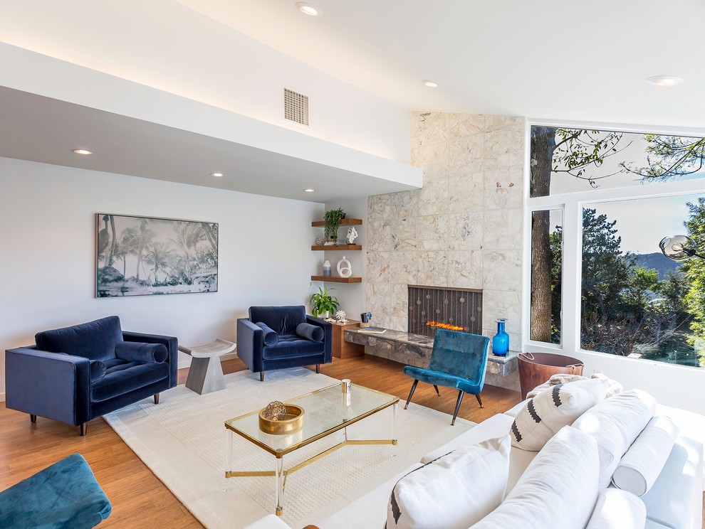 Mid-sized midcentury formal open concept living room in Los Angeles with white walls, medium hardwood floors, a standard fireplace, a stone fireplace surround and no tv.