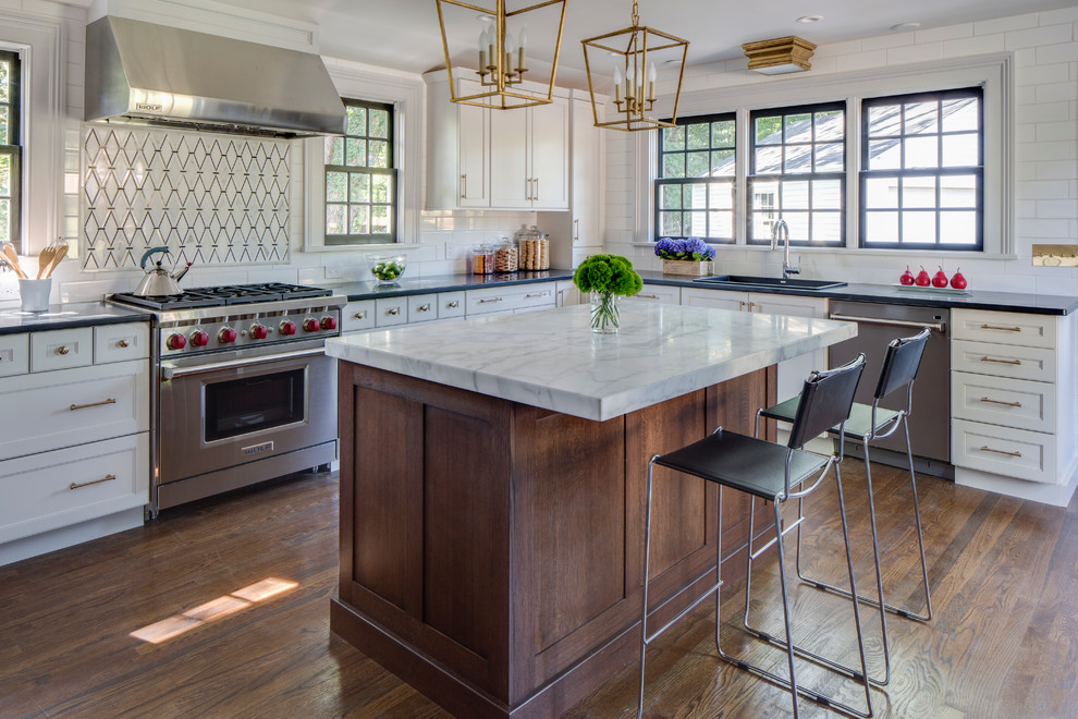 Inspiration for a mid-sized transitional l-shaped kitchen remodel in New York with recessed-panel cabinets, gray cabinets, marble countertops, white backsplash, ceramic backsplash, stainless steel appliances and an island