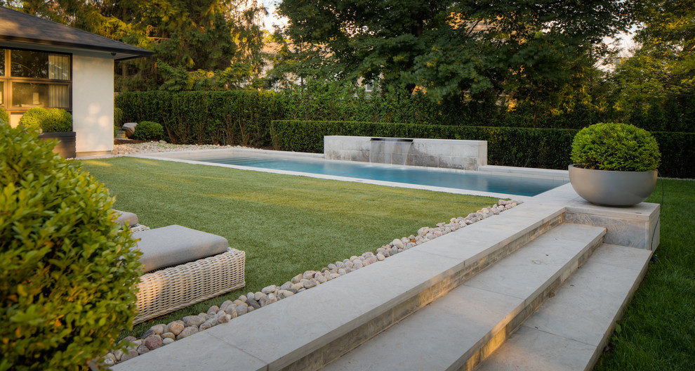 Inspiration for a large contemporary backyard rectangular lap pool in Toronto with a water feature and concrete slab.