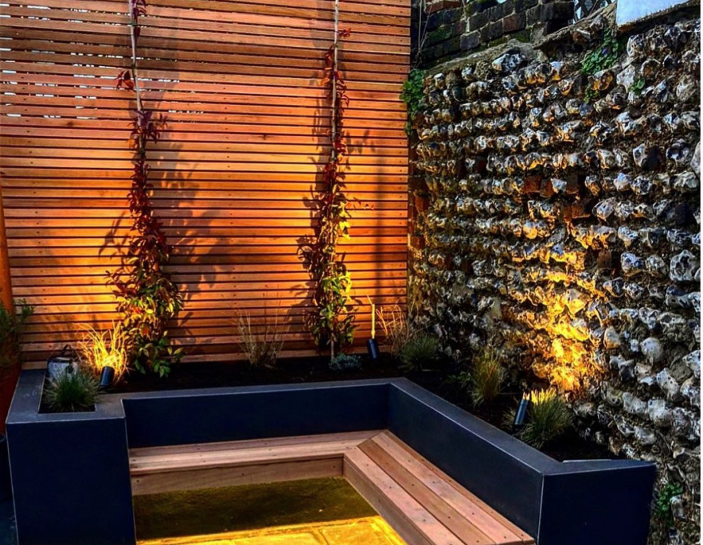 Geometrischer, Kleiner, Halbschattiger Moderner Garten im Sommer, hinter dem Haus mit Hochbeet, Natursteinplatten und Holzzaun in Sussex