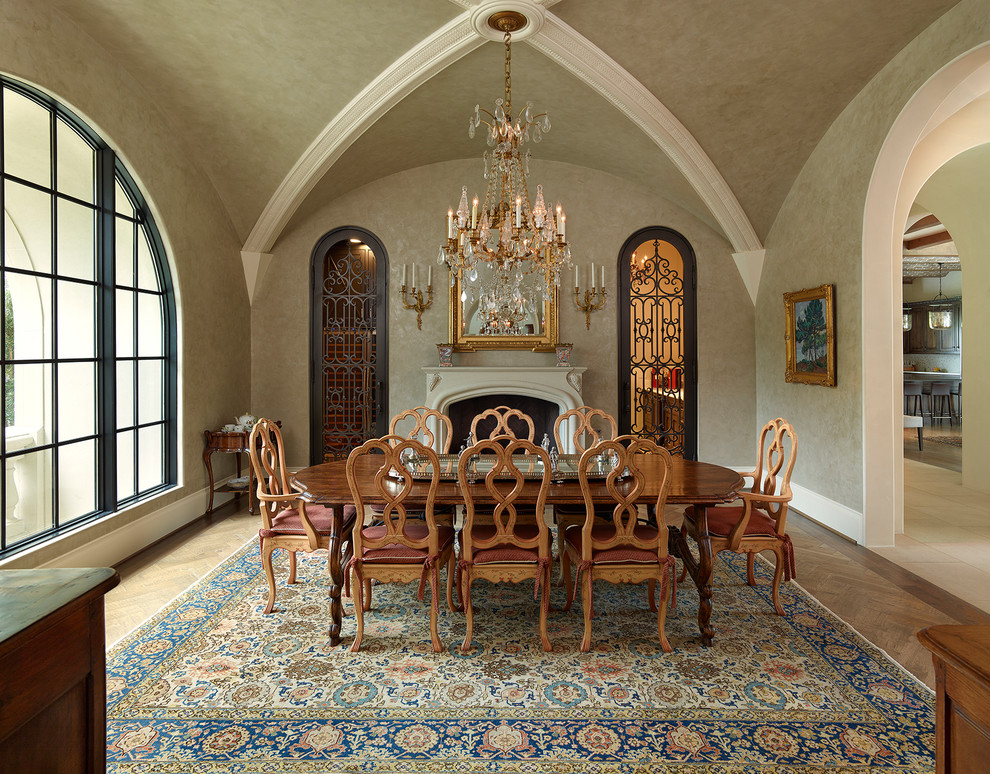 Mediterranean separate dining room in Dallas with grey walls, medium hardwood floors and a standard fireplace.