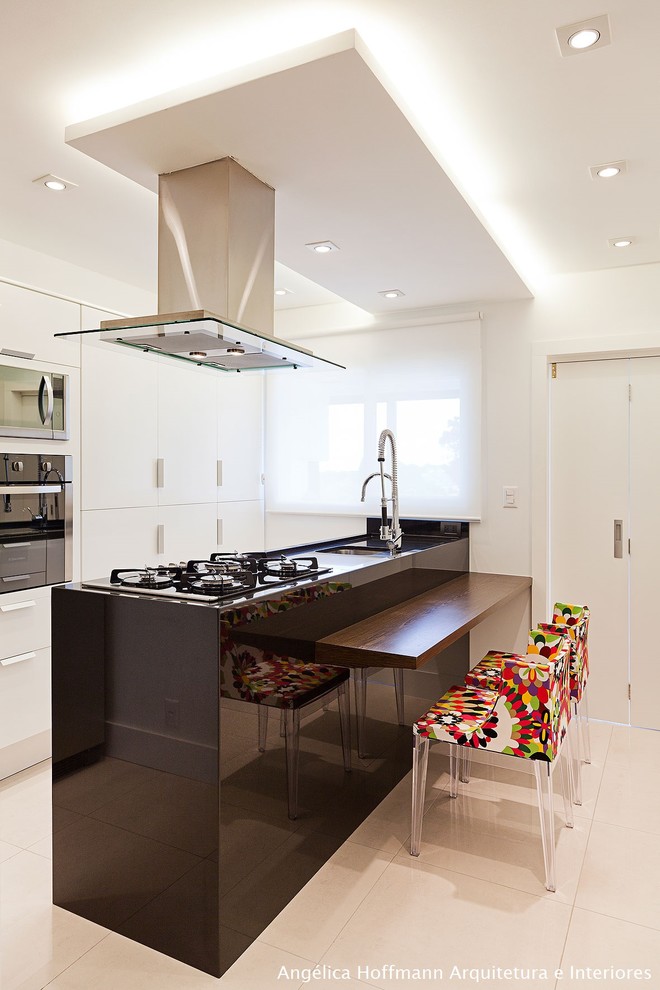Photo of a mid-sized contemporary u-shaped eat-in kitchen in Other with a drop-in sink, flat-panel cabinets, white cabinets, quartzite benchtops, black splashback, limestone splashback, stainless steel appliances, ceramic floors, multiple islands and grey floor.
