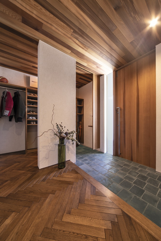 This is an example of a large midcentury entry hall in Other with white walls, a single front door, a medium wood front door and black floor.