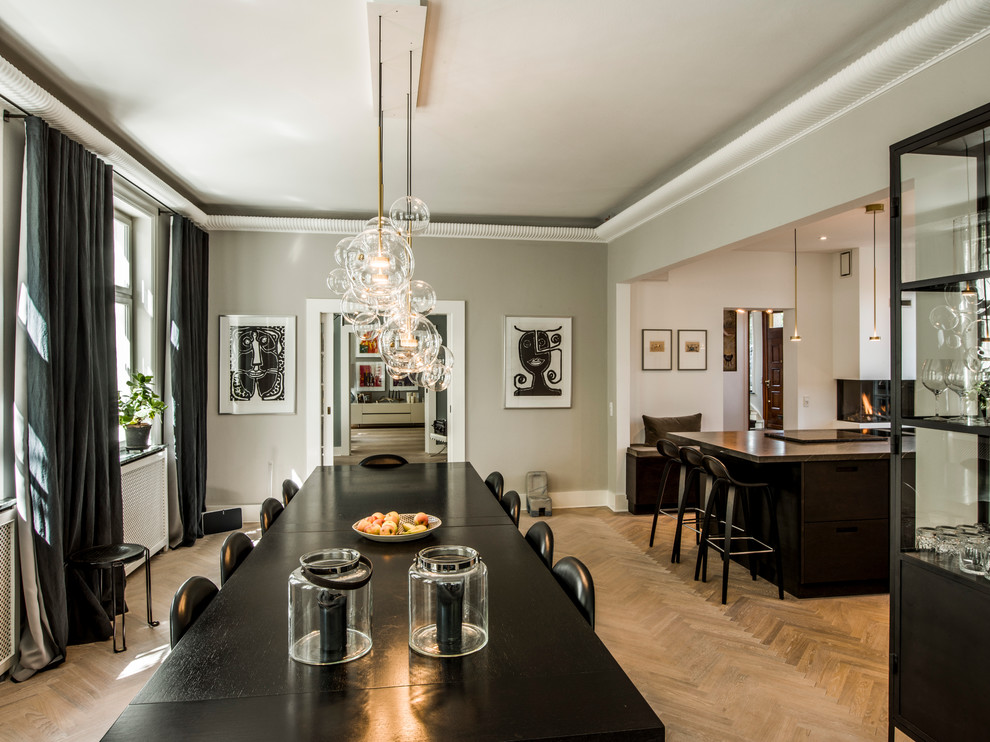 This is an example of a contemporary dining room in Copenhagen with grey walls, medium hardwood floors and brown floor.