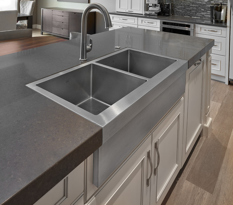 Inspiration for a large transitional l-shaped light wood floor and beige floor eat-in kitchen remodel in Edmonton with a farmhouse sink, recessed-panel cabinets, white cabinets, quartz countertops, gray backsplash, matchstick tile backsplash, stainless steel appliances and an island