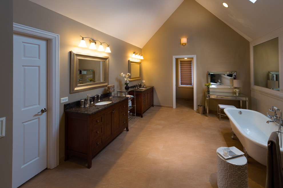This is an example of a large transitional master bathroom in Chicago with furniture-like cabinets, granite benchtops, a claw-foot tub, a double shower, a two-piece toilet, porcelain tile, beige walls, porcelain floors, dark wood cabinets, beige tile and an undermount sink.