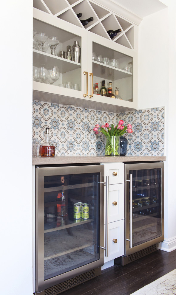 Design ideas for a mid-sized traditional galley home bar in San Diego with glass-front cabinets, white cabinets, wood benchtops, multi-coloured splashback and ceramic splashback.