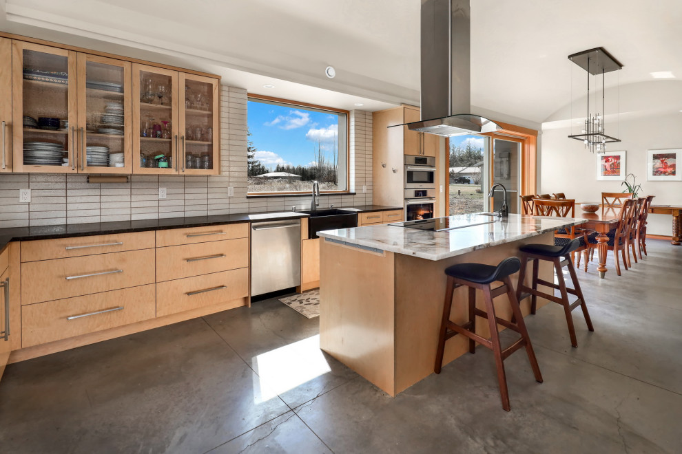 This is an example of a large country l-shaped eat-in kitchen in Seattle with a farmhouse sink, flat-panel cabinets, light wood cabinets, quartz benchtops, grey splashback, ceramic splashback, stainless steel appliances, concrete floors, with island, grey floor and multi-coloured benchtop.