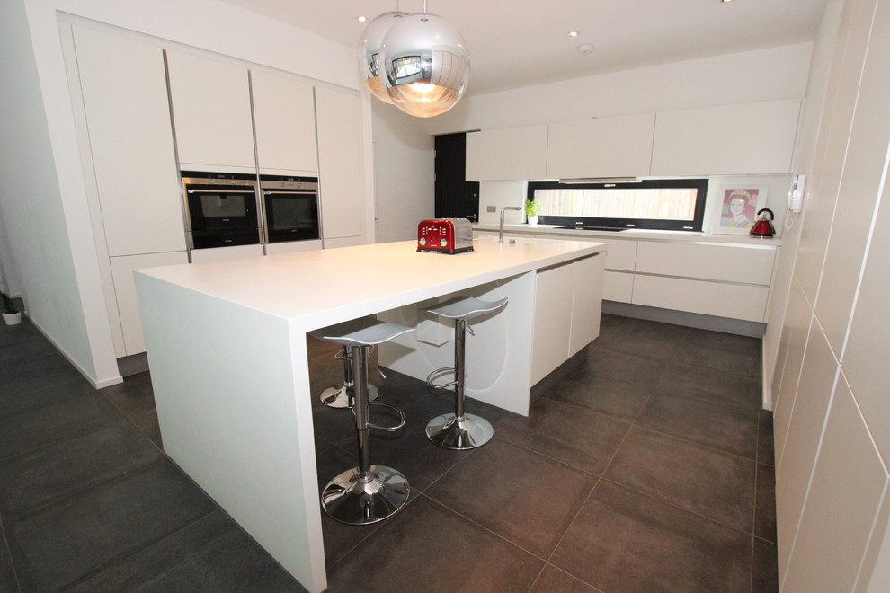 This is an example of a contemporary kitchen in London with white cabinets and with island.