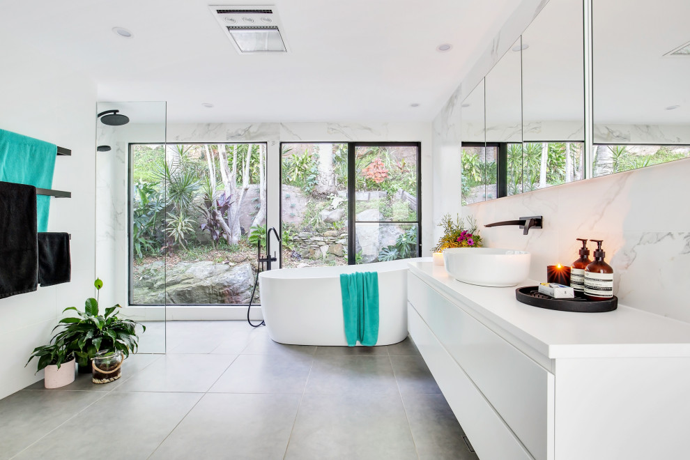 Inspiration for a large contemporary master bathroom in Sydney with raised-panel cabinets, white cabinets, a freestanding tub, an open shower, a one-piece toilet, black and white tile, ceramic tile, white walls, ceramic floors, a vessel sink, solid surface benchtops, grey floor, an open shower and white benchtops.