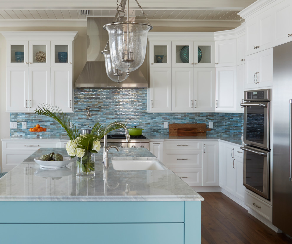 This is an example of a large beach style l-shaped open plan kitchen in Jacksonville with a farmhouse sink, recessed-panel cabinets, turquoise cabinets, quartzite benchtops, blue splashback, glass tile splashback, stainless steel appliances, medium hardwood floors, with island and brown floor.