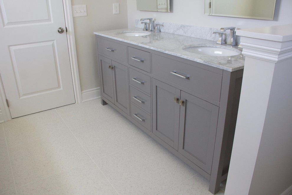 This is an example of a traditional master bathroom in Detroit with grey cabinets, a freestanding tub, white tile, ceramic tile, grey walls, terrazzo floors, an undermount sink, marble benchtops, white floor and a hinged shower door.