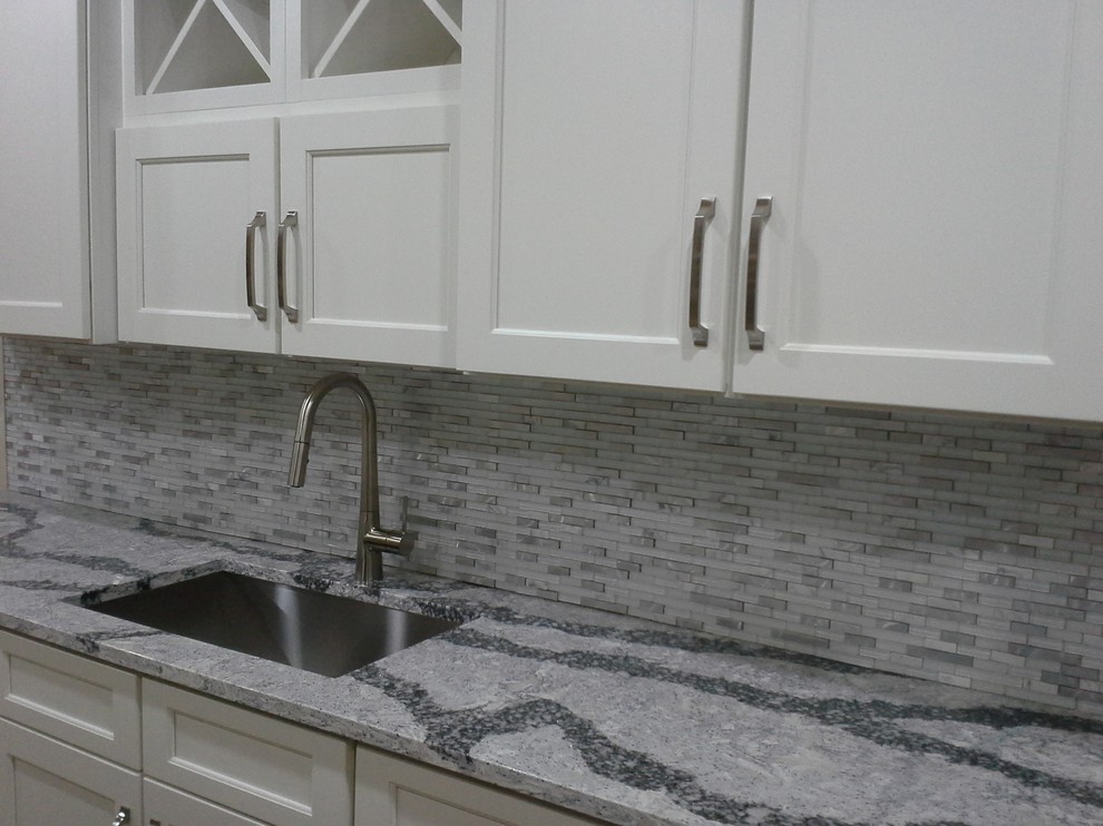 Small transitional galley kitchen photo in New York with an undermount sink, recessed-panel cabinets, white cabinets, quartz countertops, white backsplash, mosaic tile backsplash and no island