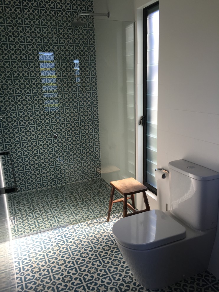 This is an example of a mid-sized contemporary kids bathroom in Sydney with furniture-like cabinets, an open shower, a one-piece toilet, blue tile, white walls, a pedestal sink and marble benchtops.