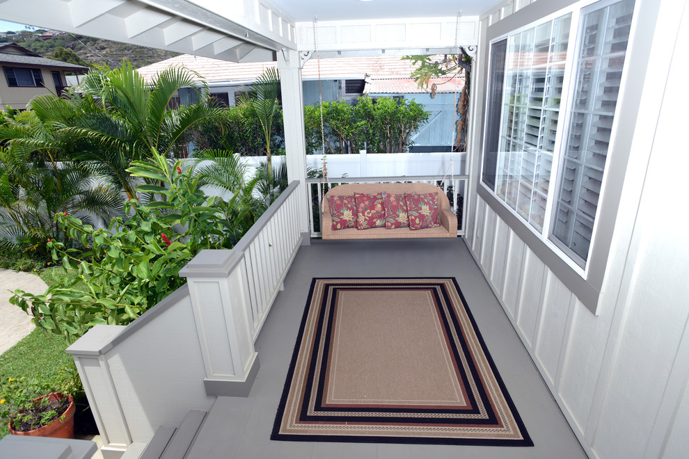 Small tropical front yard patio in Hawaii with concrete slab and a roof extension.