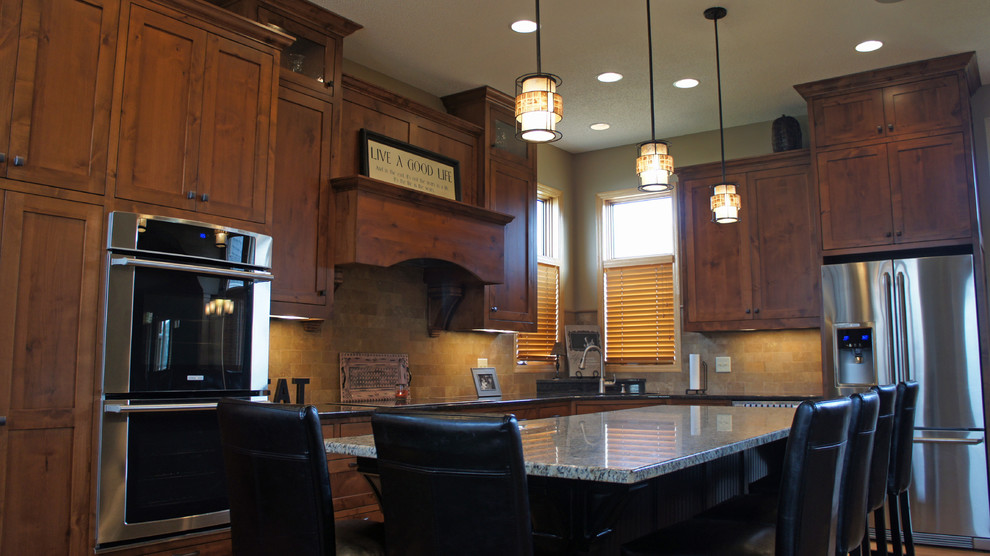 Design ideas for a large traditional l-shaped eat-in kitchen in Minneapolis with an undermount sink, shaker cabinets, dark wood cabinets, granite benchtops, yellow splashback, stone tile splashback, stainless steel appliances, medium hardwood floors and with island.