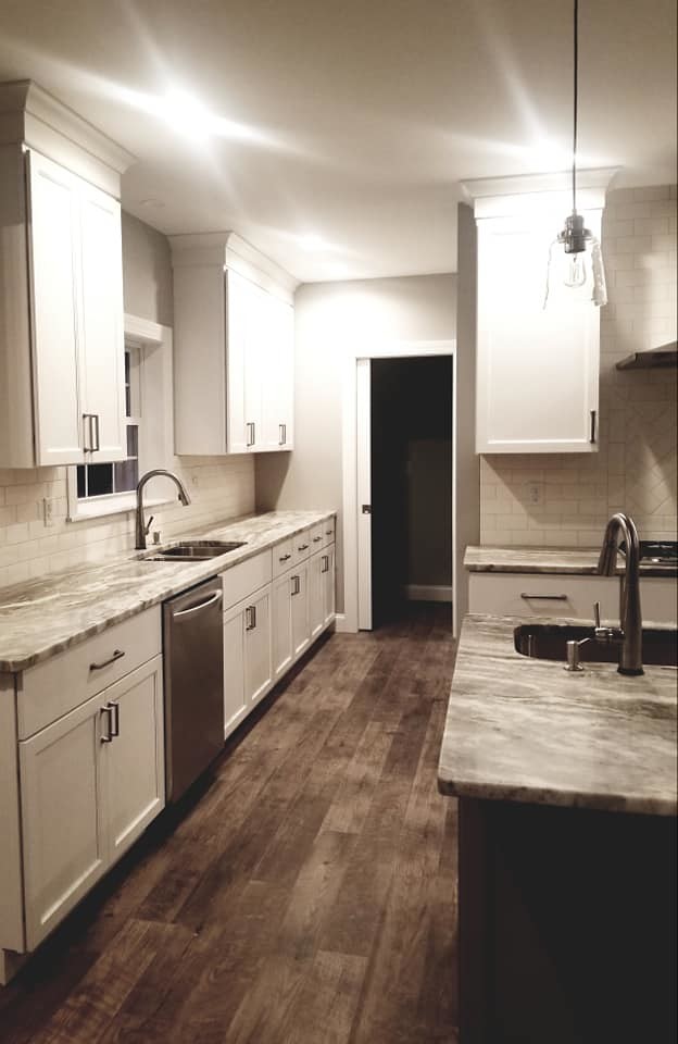 Transitional brown floor kitchen photo with an undermount sink, flat-panel cabinets, white cabinets, quartzite countertops, white backsplash, subway tile backsplash, stainless steel appliances and an island