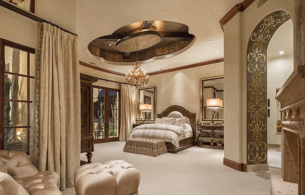 This is an example of a large mediterranean master bedroom in Phoenix with beige walls, carpet, a standard fireplace and a stone fireplace surround.