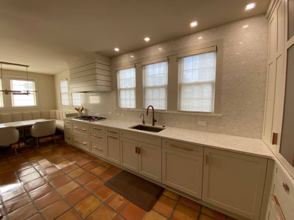 Large nautical galley kitchen in Philadelphia with a submerged sink, shaker cabinets, white cabinets, engineered stone countertops, engineered quartz splashback, stainless steel appliances and terracotta flooring.