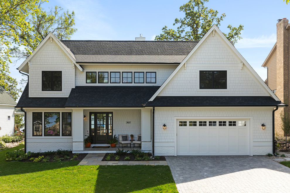 Large beach style three-storey white house exterior in Minneapolis with concrete fiberboard siding and a shingle roof.