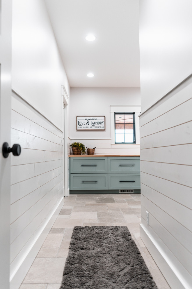 Design ideas for a large country l-shaped dedicated laundry room in Other with shaker cabinets, blue cabinets, wood benchtops, white splashback, shiplap splashback, white walls, ceramic floors, a side-by-side washer and dryer, grey floor and brown benchtop.