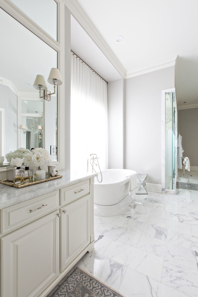 Inspiration for a transitional master bathroom in Orange County with raised-panel cabinets, white cabinets, a freestanding tub, an alcove shower, gray tile, white tile, stone tile, grey walls, marble floors and marble benchtops.