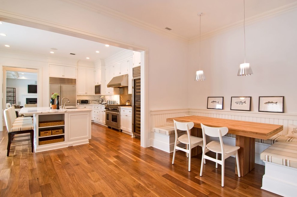 Example of a large transitional l-shaped medium tone wood floor and brown floor eat-in kitchen design with a farmhouse sink, recessed-panel cabinets, white cabinets, marble countertops, white backsplash, marble backsplash, stainless steel appliances and an island
