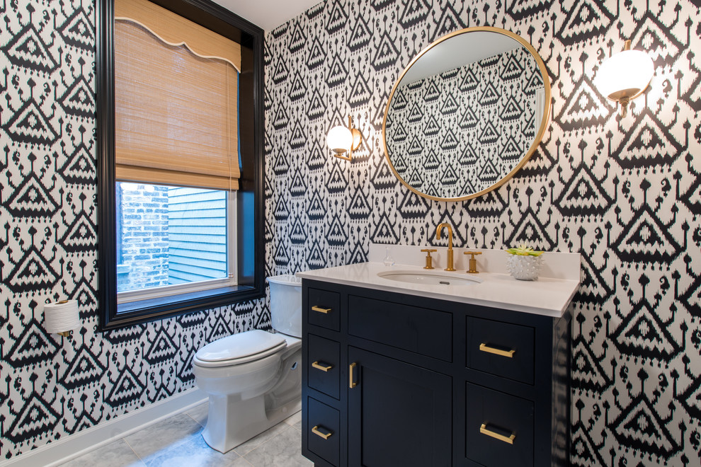 This is an example of a transitional powder room in Chicago with shaker cabinets, blue cabinets, a two-piece toilet, an undermount sink, grey floor and white benchtops.