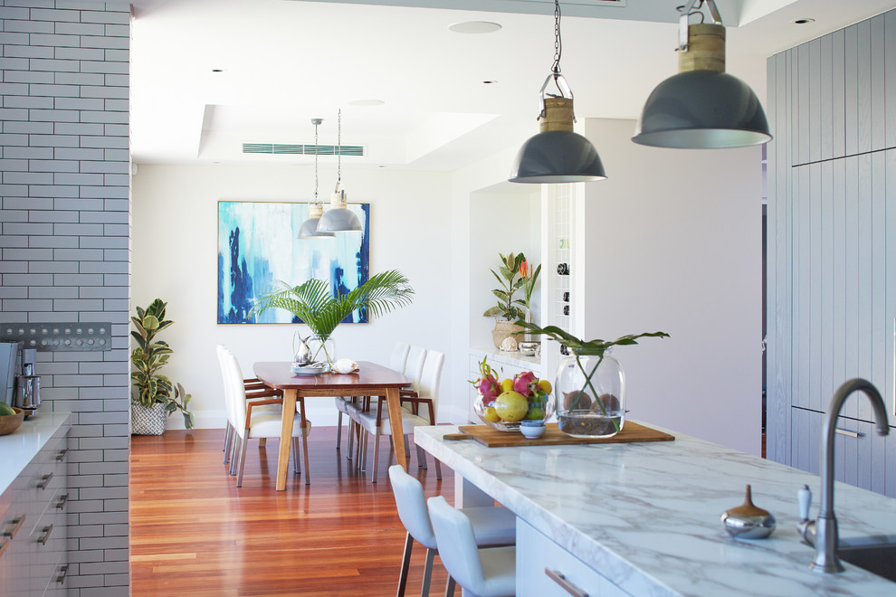Inspiration for a large beach style u-shaped eat-in kitchen in Perth with an undermount sink, flat-panel cabinets, marble benchtops, white splashback, subway tile splashback, medium hardwood floors and with island.