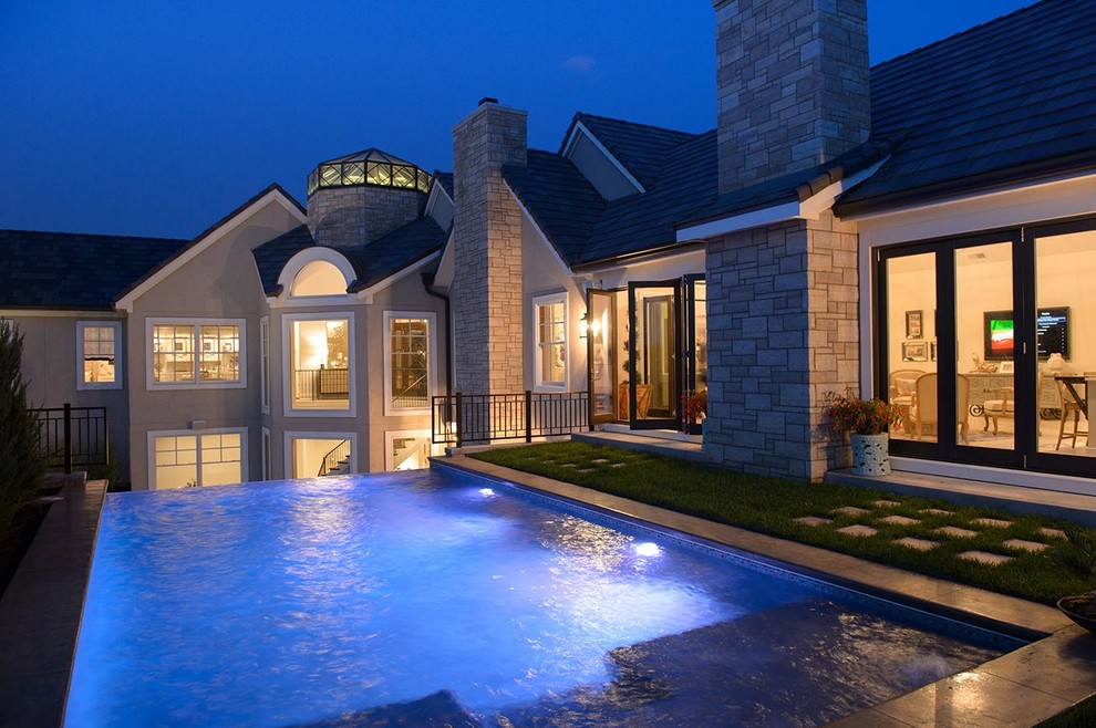 Photo of a mid-sized side yard rectangular infinity pool in Kansas City with concrete pavers.