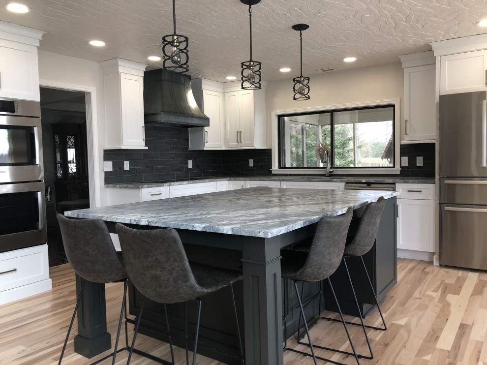 Inspiration for a large modern l-shaped eat-in kitchen in Indianapolis with a single-bowl sink, shaker cabinets, white cabinets, granite benchtops, grey splashback, subway tile splashback, stainless steel appliances, light hardwood floors, with island, brown floor and grey benchtop.