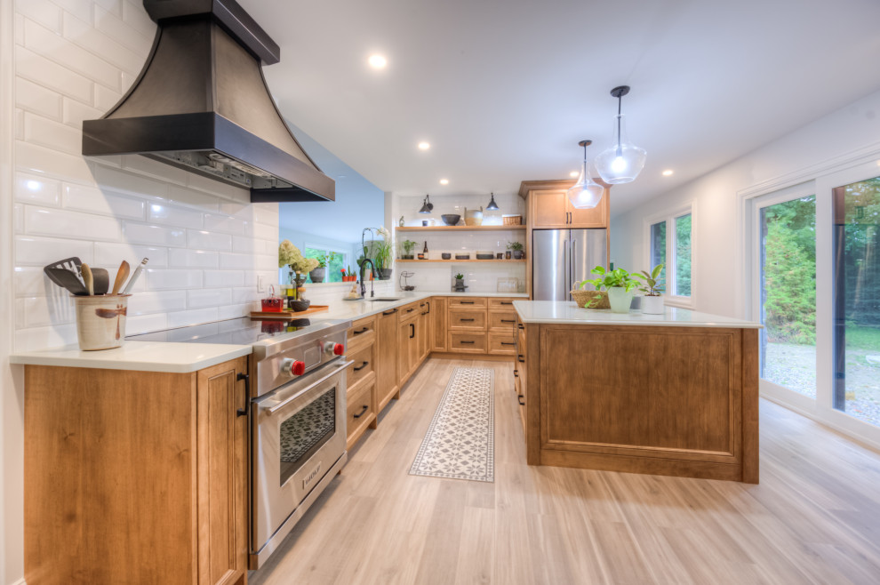 Kitchen - transitional l-shaped kitchen idea in Toronto with an undermount sink, shaker cabinets, light wood cabinets, white backsplash, stainless steel appliances, an island and white countertops