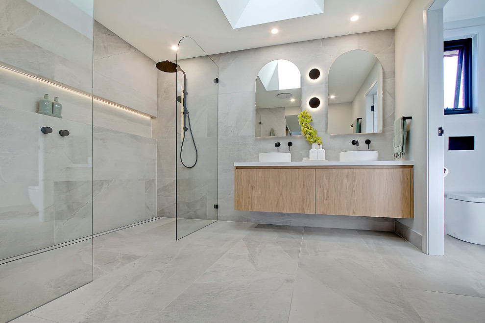 Inspiration for a large modern master bathroom in Sydney with flat-panel cabinets, medium wood cabinets, a double shower, a one-piece toilet, gray tile, porcelain tile, grey walls, porcelain floors, a vessel sink, engineered quartz benchtops, grey floor, an open shower, white benchtops, a niche, a double vanity and a floating vanity.