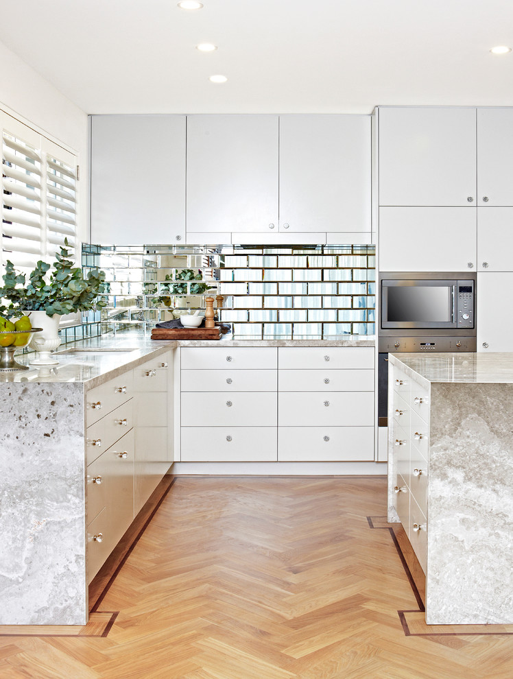 Inspiration for a transitional kitchen in Sydney with an undermount sink, flat-panel cabinets, white cabinets, metallic splashback, subway tile splashback, light hardwood floors and with island.