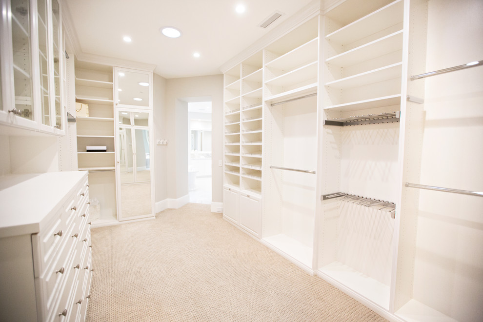 Inspiration for a large transitional gender-neutral walk-in wardrobe in Orange County with glass-front cabinets, white cabinets and carpet.