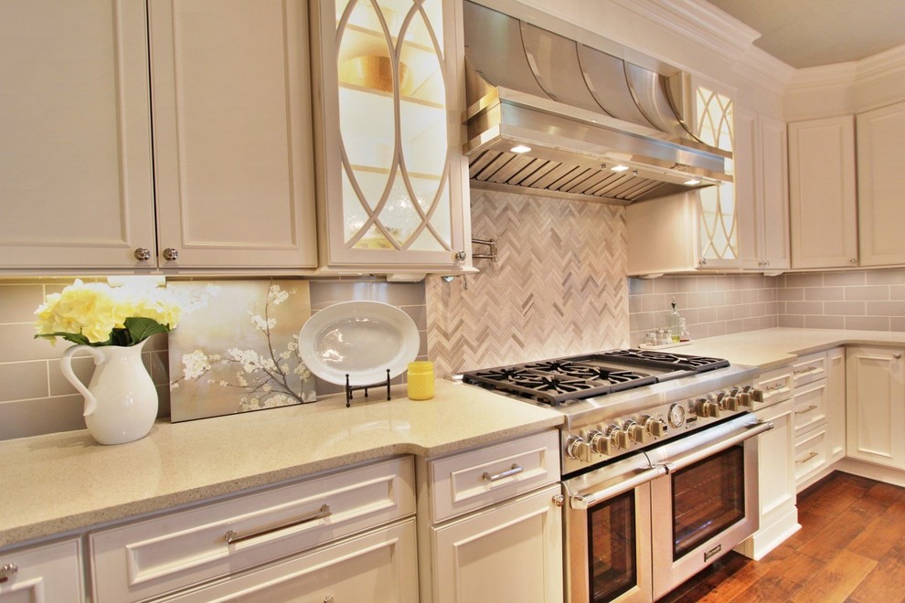 Example of a large l-shaped medium tone wood floor eat-in kitchen design with a double-bowl sink, white cabinets, granite countertops, gray backsplash, glass tile backsplash, stainless steel appliances and an island