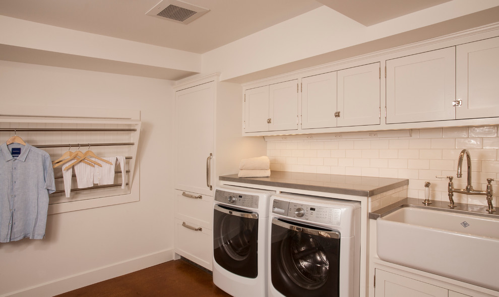 Inspiration for a mid-sized transitional u-shaped dedicated laundry room in Seattle with a farmhouse sink, shaker cabinets, white cabinets, zinc benchtops, white walls, concrete floors and a side-by-side washer and dryer.