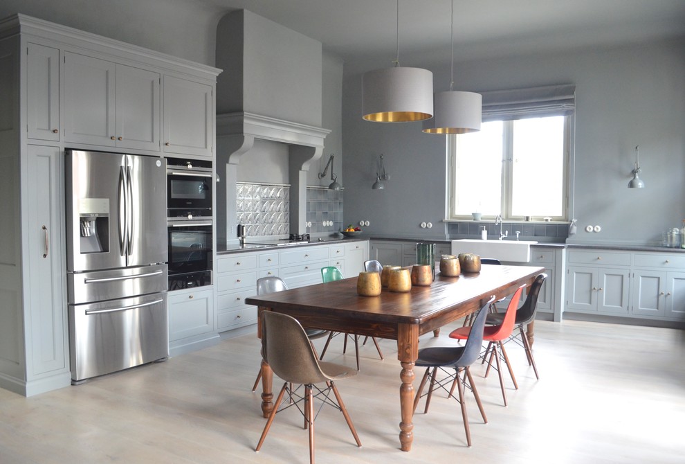 Inspiration for an expansive country l-shaped eat-in kitchen in Berlin with a farmhouse sink, blue splashback, black appliances, light hardwood floors, shaker cabinets, blue cabinets and no island.