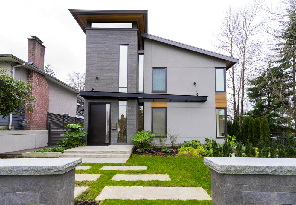 Photo of a mid-sized modern three-storey grey house exterior in Vancouver with mixed siding and a shed roof.