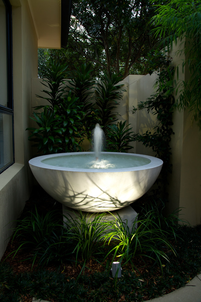 Photo of a small tropical courtyard shaded garden in Sydney with a water feature and natural stone pavers.
