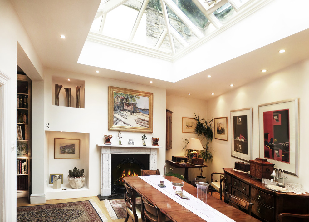 Photo of a large traditional separate dining room in London with a stone fireplace surround, white walls, dark hardwood floors and a standard fireplace.