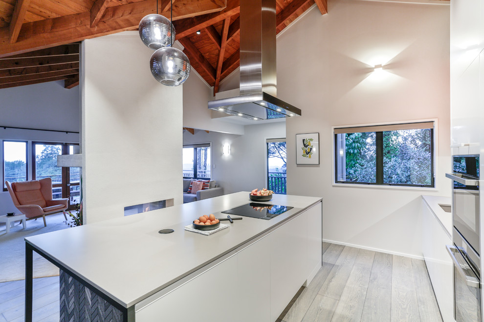 Design ideas for a mid-sized modern galley eat-in kitchen in Auckland with a single-bowl sink, flat-panel cabinets, orange cabinets, quartz benchtops, black splashback, porcelain splashback, black appliances, painted wood floors, with island, grey floor and grey benchtop.